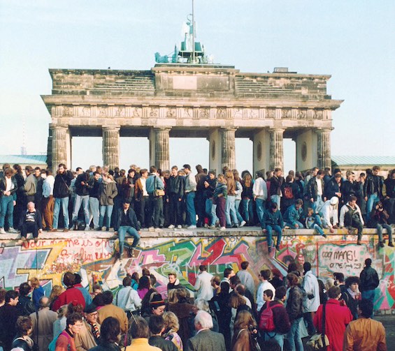 Photo of people gathering atop the Berlin Wall just before the Wall fell