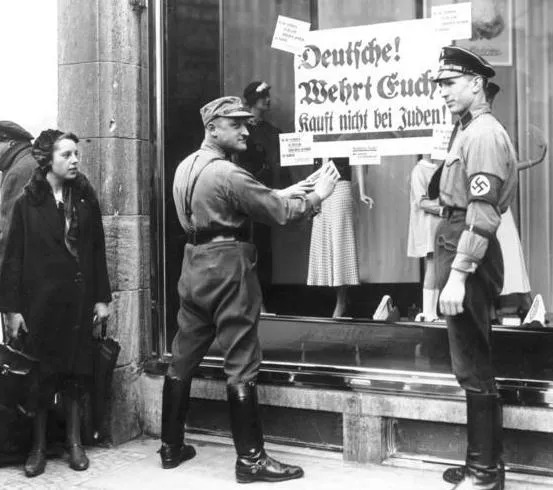 Photo of brownshirts posting a warning on a Jewish shop not to buy goods there, an event that alarms the principals in this anti-Nazi novel