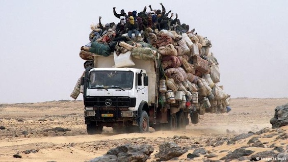 Photo of a truck crossing the Sahara Desert, crammed with illegal migrants from sub-Saharan Africa en route to Europe, like the young couple in this novel about a missing-persons case