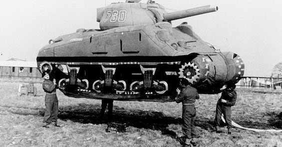 Image of men holding up one of the 93-pound rubber tanks used in the Ghost Army's deception in World War II